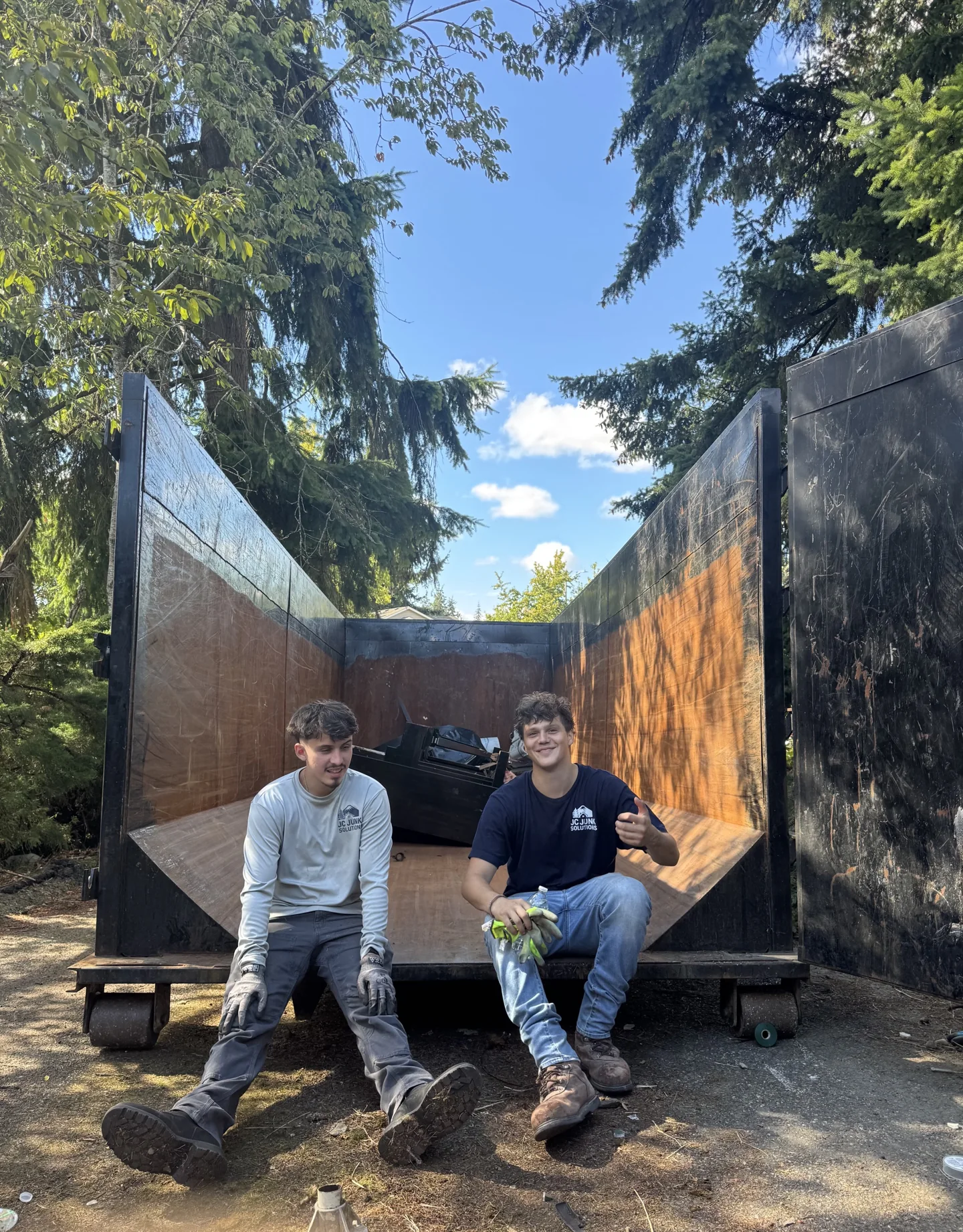 Two JC Junk Solutions crew members seated at the back of their hauling truck