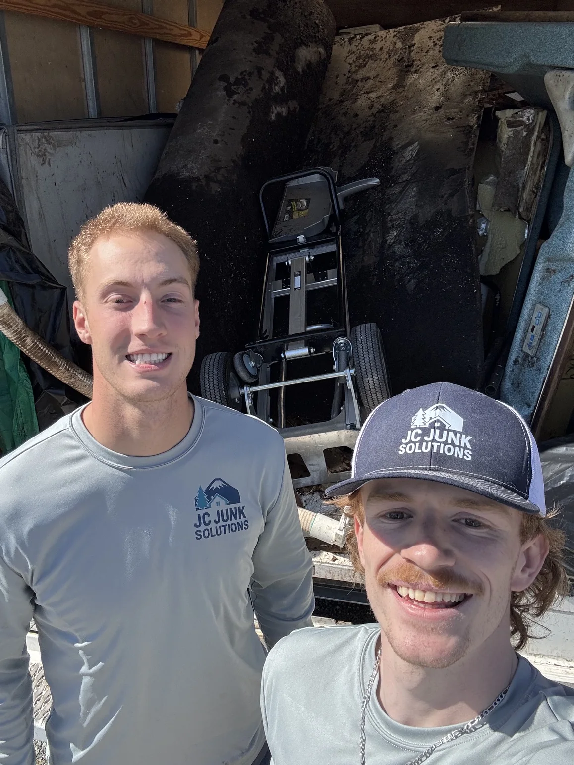 Two JC Junk Solutions crew members beside a loaded hauling truck