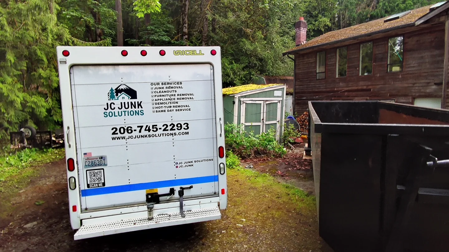 JC Junk Solutions box truck parked beside a home for a pickup