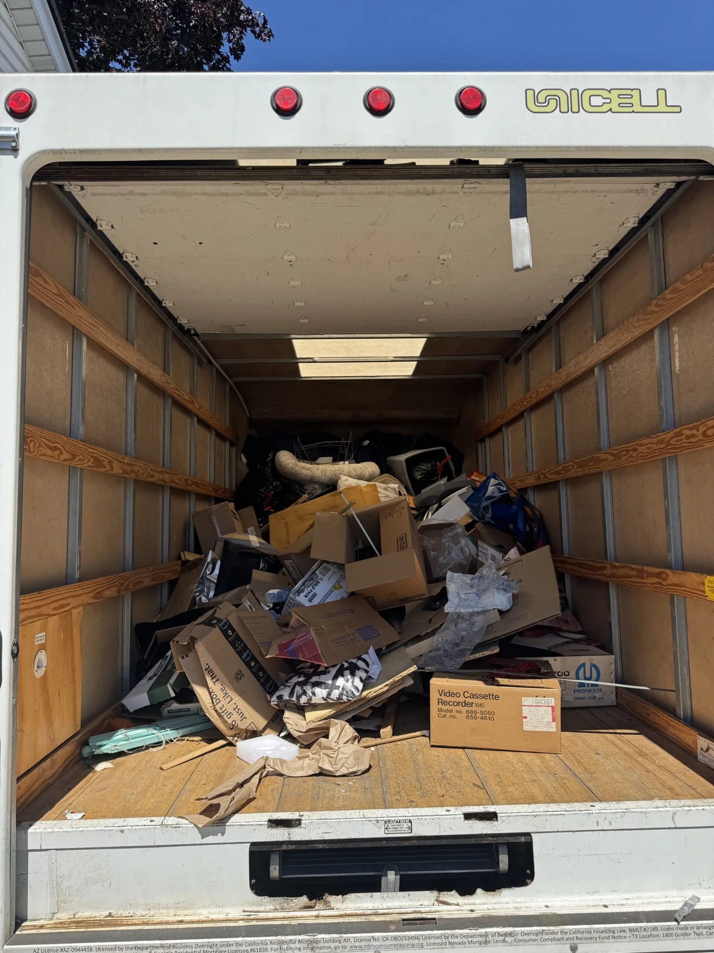Open box truck carrying household items and boxes during a JC Junk Solutions pickup